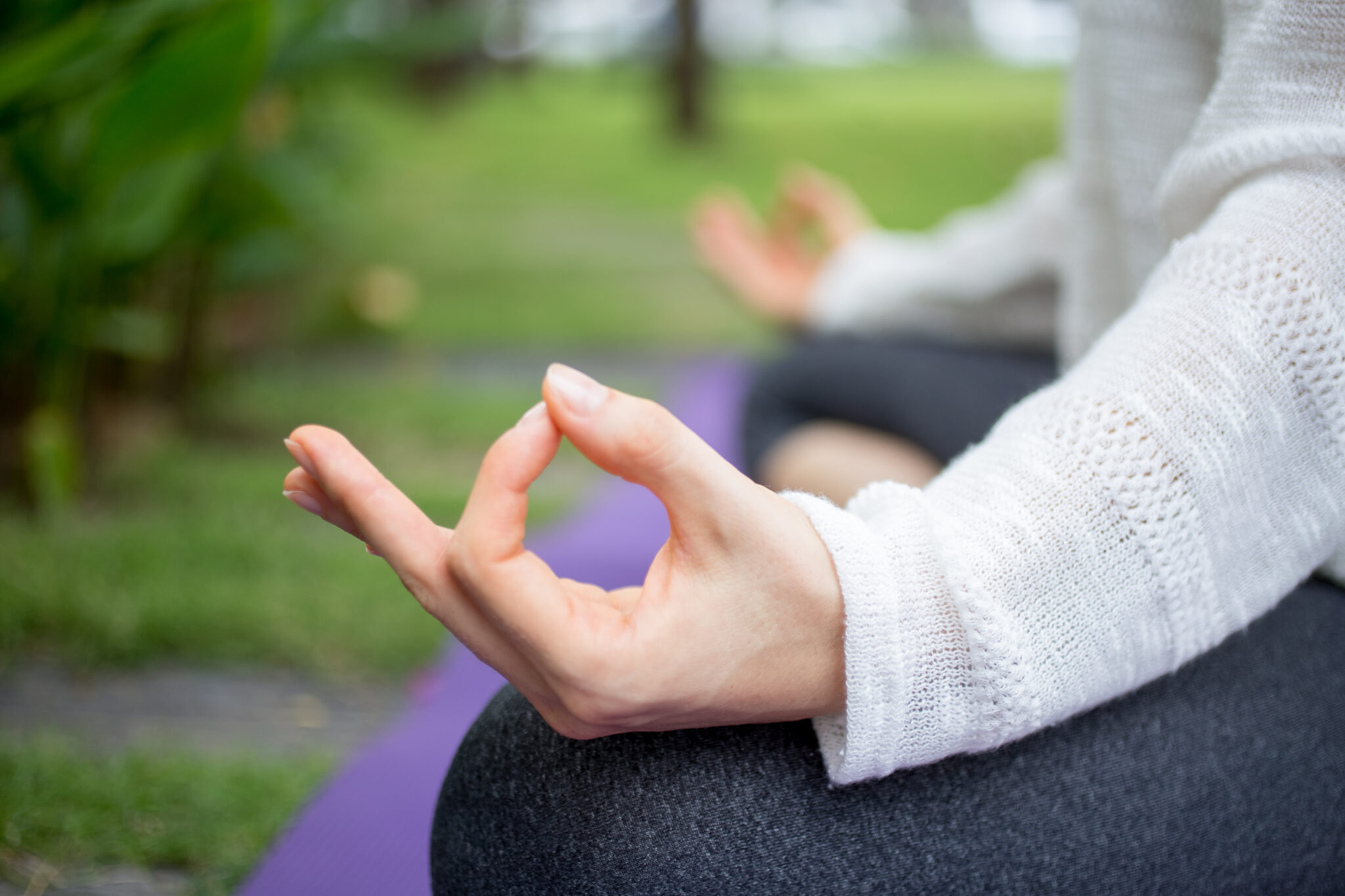 Close-up of hand in a zen gesture during outdoor meditation, a peaceful tech-free hobby for mental clarity