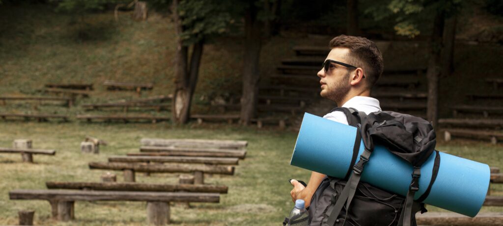 Person with a backpack holding a yoga mat, enjoying tech-free hobbies like hiking and yoga outdoors